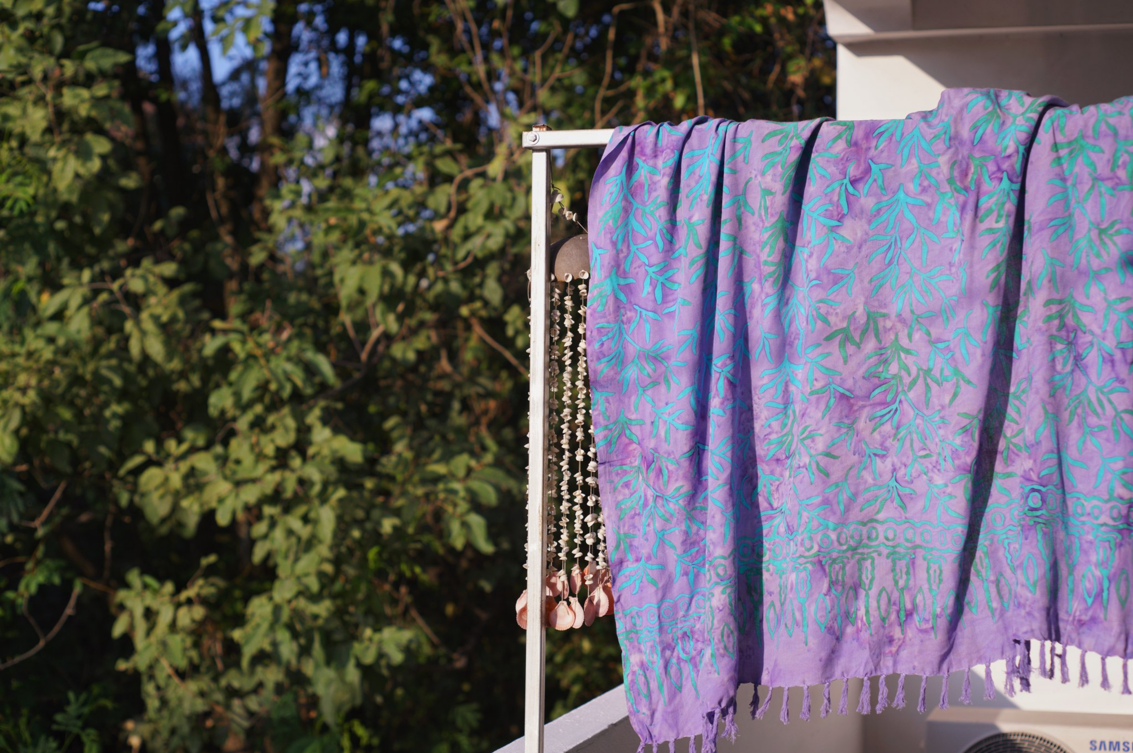 The Lanta Reef - Lavender sarong from YUMI & KORA hangs in the sunshine by some trees