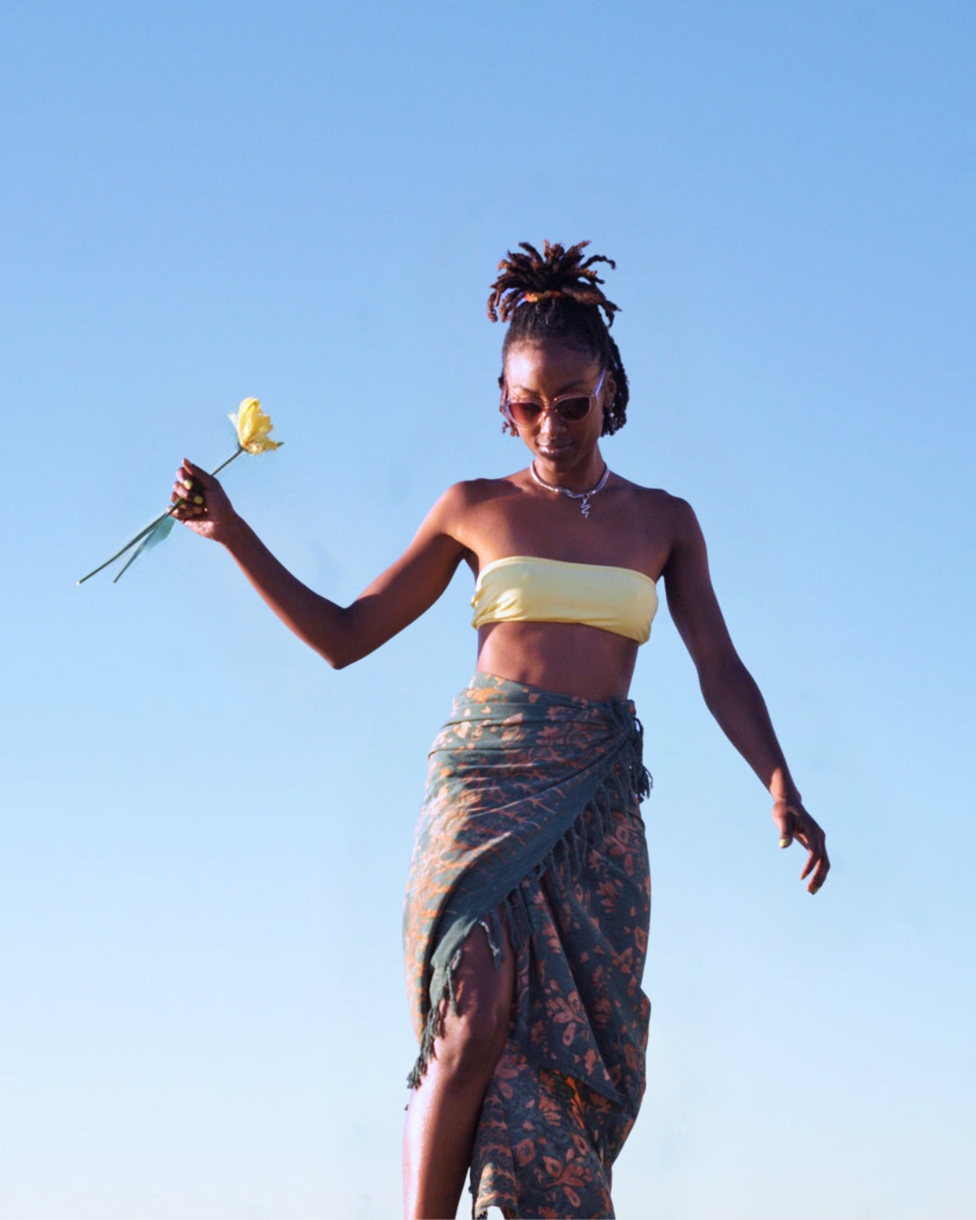 A woman wears the Lily & Lotus - Forest Green sarong from YUMI & KORA as a swimsuit cover-up skirt. Our sarongs can be tied as a skirt, a dress, or a beach kimono