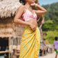 A woman wears the Lanta Reef - Yellow sarong from YUMI & KORA as a swimsuit cover-up skirt at the beach