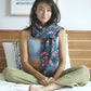 A woman wears the Butterfly - Dark Slate sarong from YUMI & KORA as a scarf. Our sarongs can be used as a light shawl or as a light scarf for tropical winters