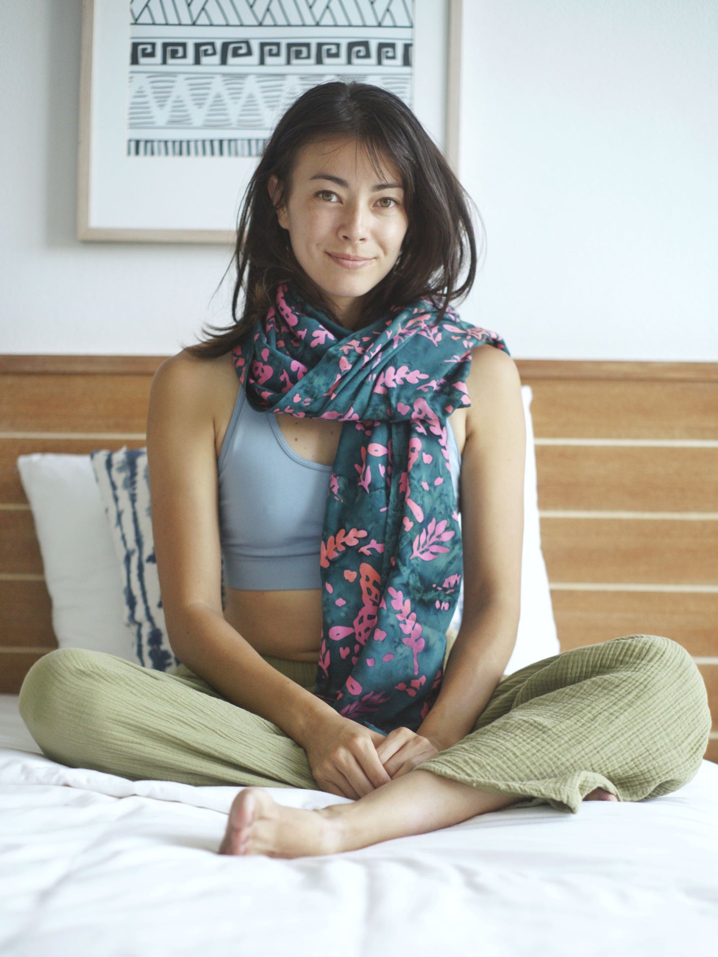 A woman wears the Butterfly - Dark Slate sarong from YUMI & KORA as a scarf. Our sarongs can be used as a light shawl or as a light scarf for tropical winters