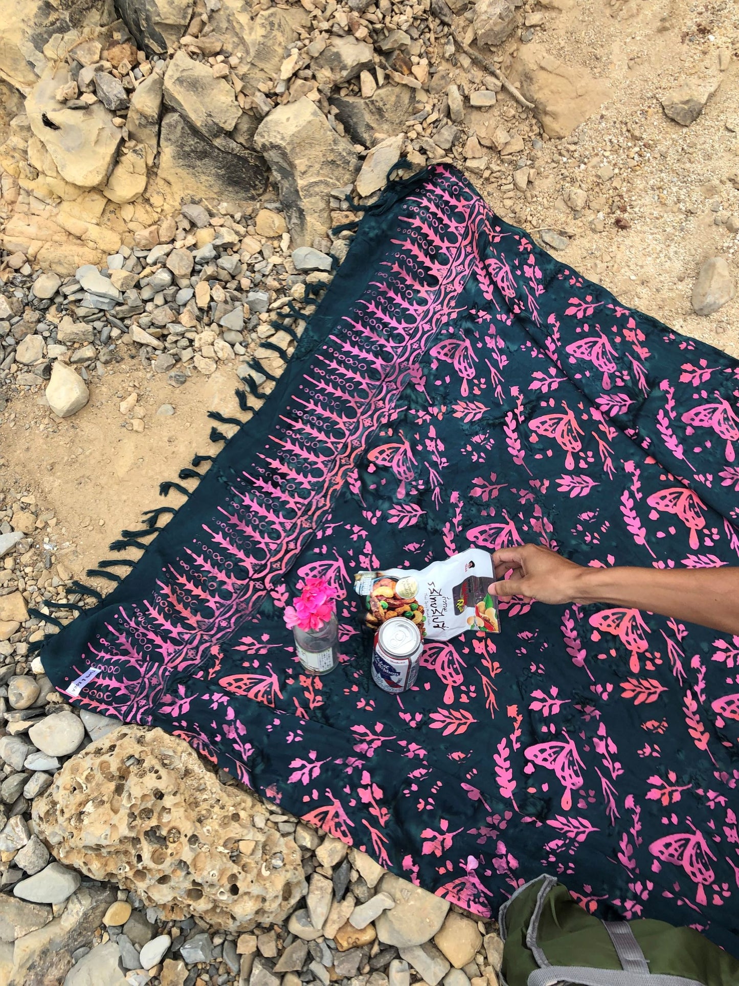 The Butterfly - Dark Slate sarong from YUMI & KORA is used as a picnic blanket by the beach