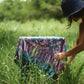 The Butterfly - Dark Slate sarong from YUMI & KORA is used as a tablecloth. A woman adjusts the sarong on a small table