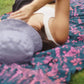 A woman lays on the Butterfly - Dark Slate sarong from YUMI & KORA. Our sarongs can be used as a picnic blanket or as a beach towel
