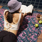 A woman lays on the Butterfly - Dark Slate sarong from YUMI & KORA by the pool. Our sarongs can be used as a pool towel or a beach towel