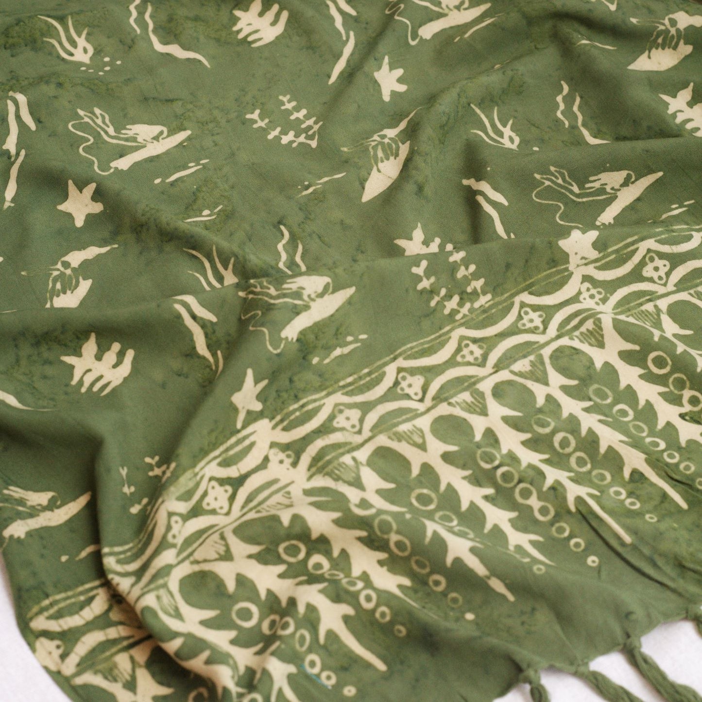 The Duck Dive - Olive Green sarong from YUMI & KORA features a pattern of women surfing, starfish, and seaweed