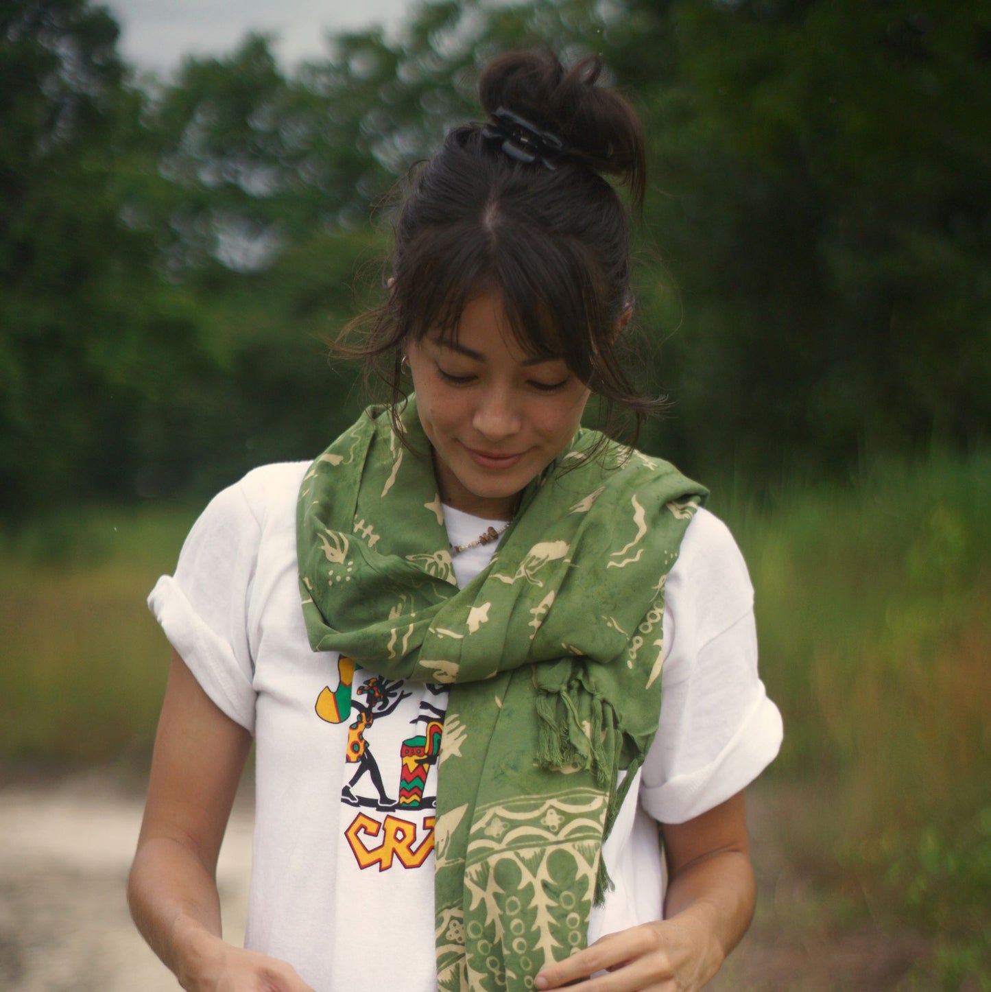 A woman wears the Duck Dive - Olive Green sarong from YUMI & KORA as a light scarf. Our sarongs can be wrapped as a scarf or as a shawl