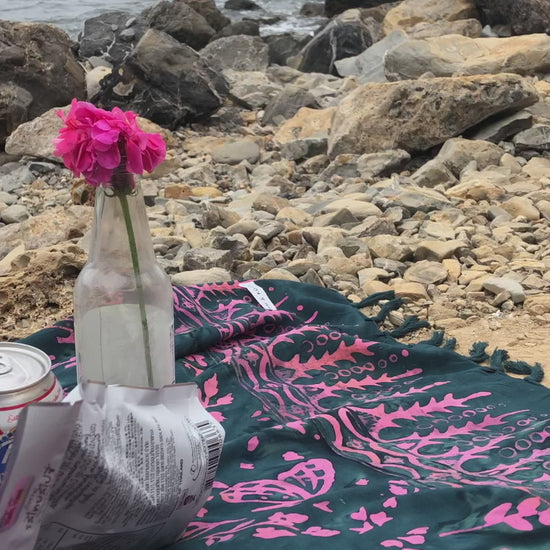 The Butterfly - Dark Slate sarong from YUMI & KORA is used as a picnic blanket by the beach
