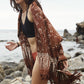 A woman wears the Hin Kong Bay - Brown sarong from YUMI & KORA as a shawl over her swimsuit. Our sarongs can be used as a shawl or a scarf on chilly summer days and nights