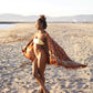 A woman holds the Hin Kong Bay - Brown sarong from YUMI & KORA at the beach. Our sarongs can be worn as a swimsuit cover-up at the beach or pool