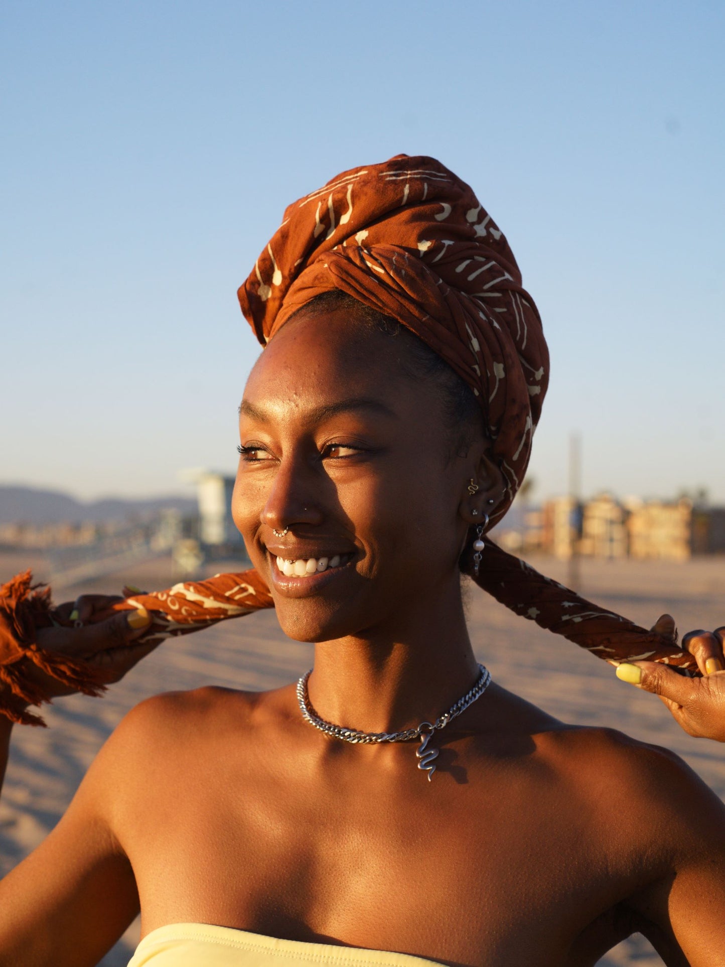 A woman wraps the Hin Kong Bay - Brown sarong from YUMI & KORA as a head scarf. Our versatile sarongs can be worn and used in many different ways