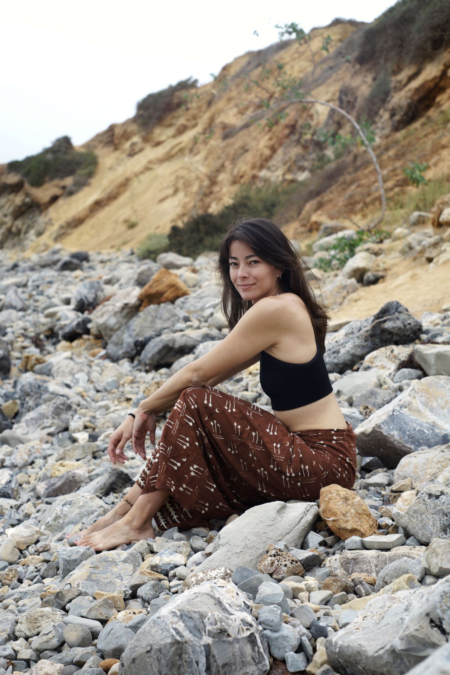 A woman wears the Hin Kong Bay - Brown sarong from YUMI & KORA as a skirt. Our sarongs can be tied as a skirt or a dress. Our sarongs are useful as a swimsuit coverup