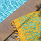 The Lanta Reef - Yellow sarong from YUMI & KORA sits on the ground by the pool as a pool towel