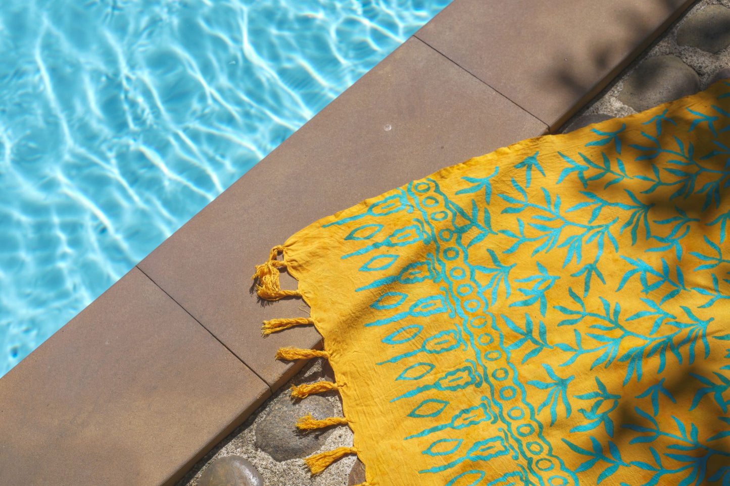 The Lanta Reef - Yellow sarong from YUMI & KORA sits on the ground by the pool as a pool towel