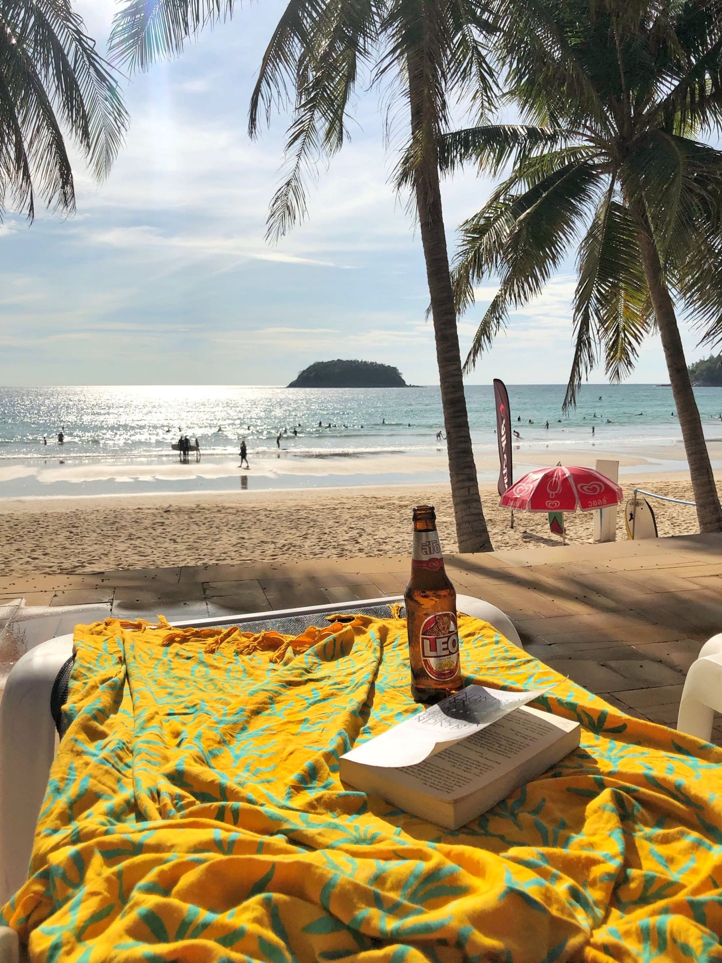 The Lanta Reef - Yellow sarong from YUMI & KORA is used as a beach towel. A beer and a book sit on top of the sarong