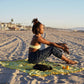 The Lanta Reef - Yellow sarong from YUMI & KORA is used as a beach towel. A woman sits on top of the sarong at the beach