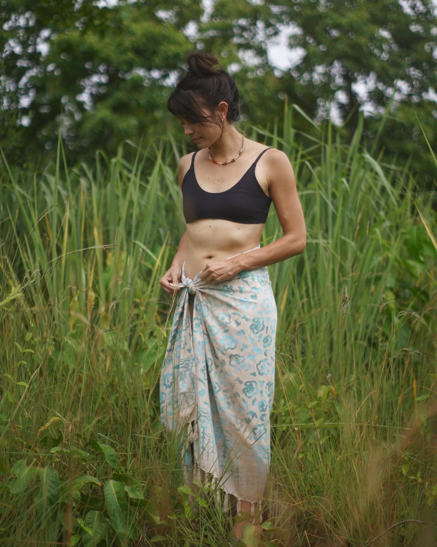 A woman wears the Summer Bloom - Ivory sarong from YUMI & KORA as a skirt. Our sarongs can be tied into a skirt or a dress. Our sarongs work great as a swimsuit coverup at the beach or by the pool