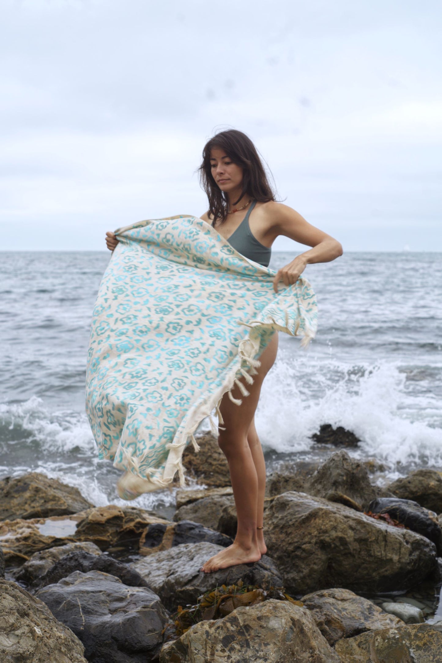 A woman holds the Summer Bloom - Ivory sarong from YUMI & KORA. Our sarongs can be tied into a skirt or a dress, or used as a beach towel