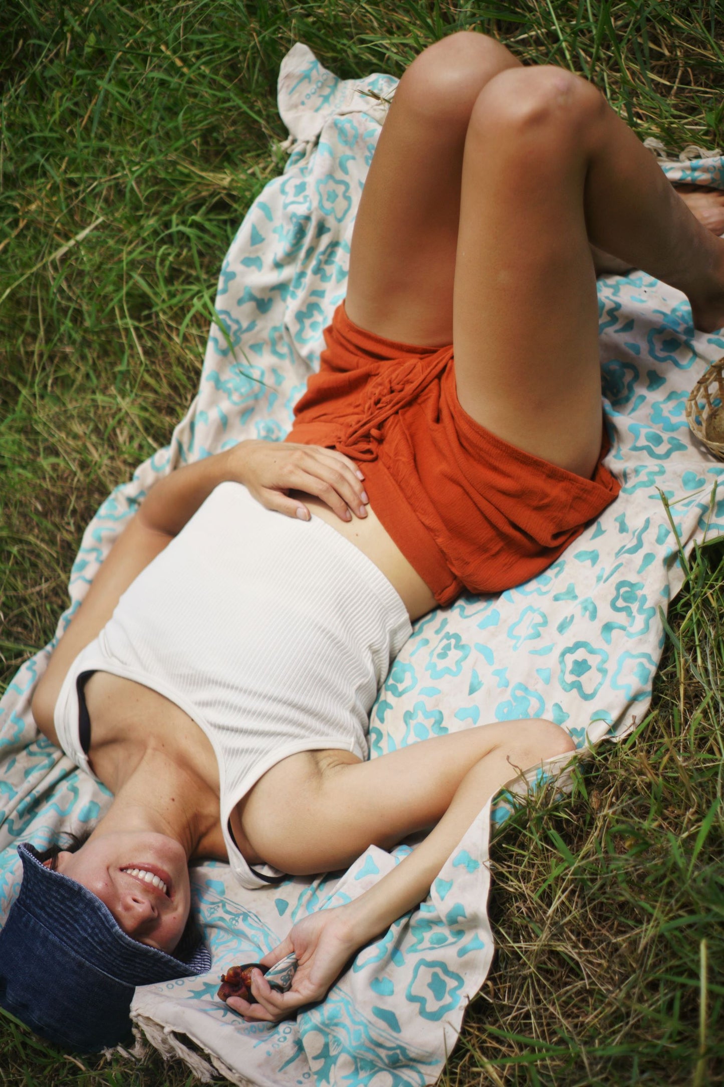 A woman lays on the Summer Bloom - Ivory sarong from YUMI & KORA. Our sarongs can be used as a picnic blanket or as a beach towel