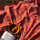 The Sweet Cosmos - Pink sarong from YUMI & KORA is used as a picnic blanket. A book and some cherry tomatoes sit on top of the sarong