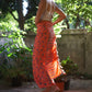 A woman wears the Sweet Cosmos - Pink sarong from YUMI & KORA as a skirt, paired with a white crop top