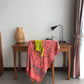 The Sweet Cosmos - Pink sarong from YUMI & KORA hangs on the back of a chair. Our sarongs can be used as a swimsuit coverup - perfect when tied as a skirt or a dress