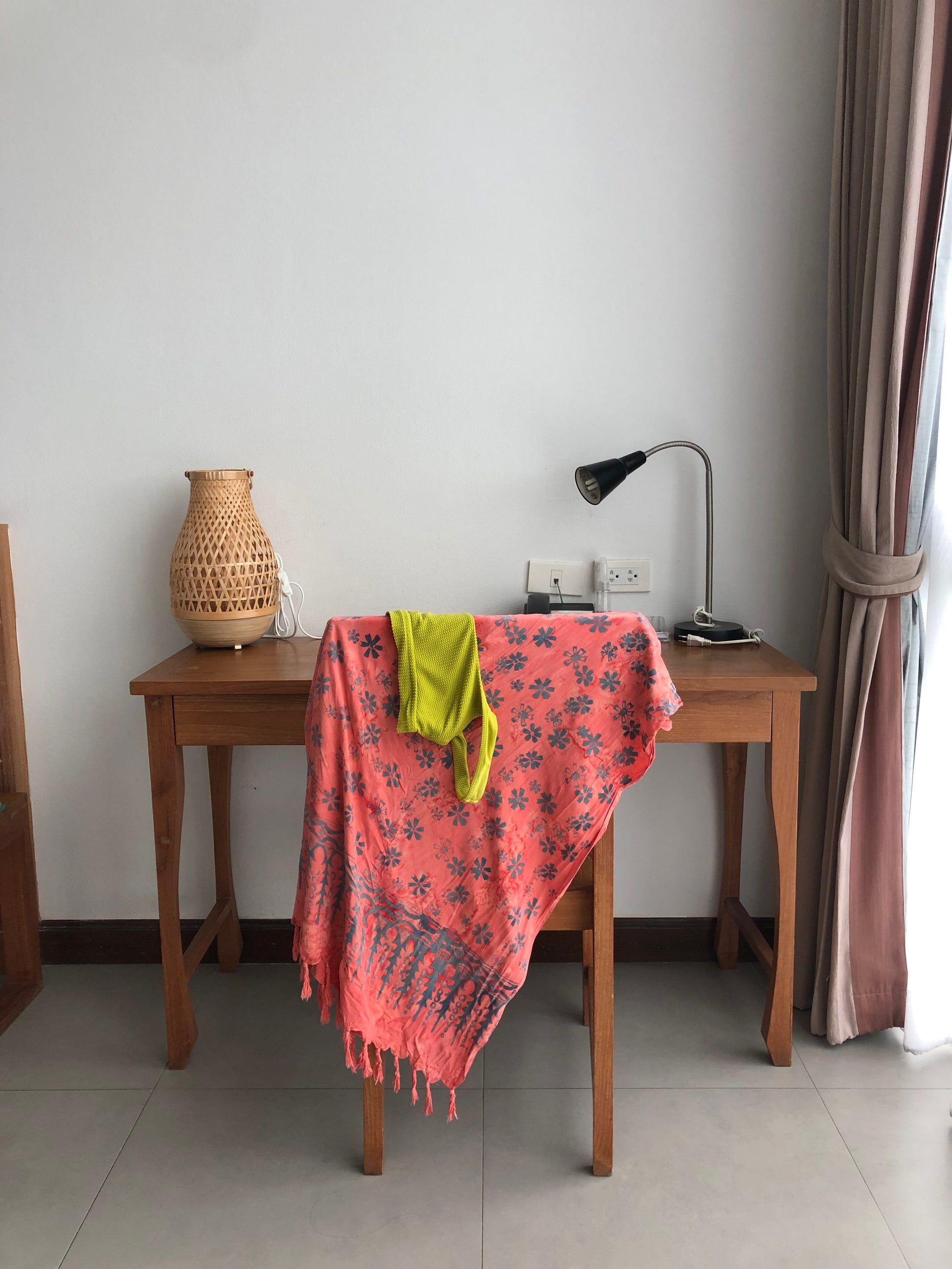 The Sweet Cosmos - Pink sarong from YUMI & KORA hangs on the back of a chair. Our sarongs can be used as a swimsuit coverup - perfect when tied as a skirt or a dress