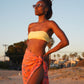 A woman wears the Sweet Cosmos - Pink sarong from YUMI & KORA as a swimsuit cover-up skirt at the beach. Our sarongs can be tied as a skirt, a dress, or a beach kimono