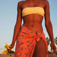 A woman wears the Sweet Cosmos - Pink sarong from YUMI & KORA as a swimsuit cover-up skirt at the beach. Our sarongs can be tied as a skirt, a dress, or a beach kimono